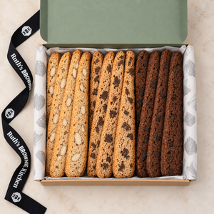 Overhead view of three biscotti varieties in Ruth’s kraft gift box with branded tissue and ribbon