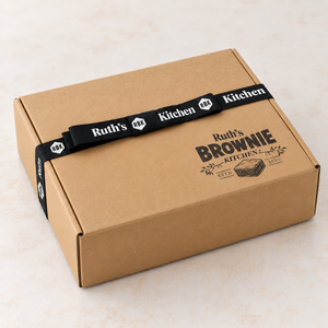Closed Ruth’s Brownie Kitchen kraft cookie gift box with printed lid logo and black branded ribbon