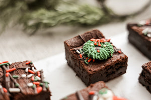 Close-up of Christmas Extra Fudgy Brownie with piped green wreath icing and red bow