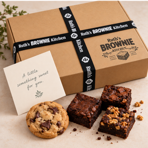 Closed Ruth's Brownie Kitchen kraft gift box with original logo and black RBK ribbon, alongside assorted gluten-free brownies and cookie